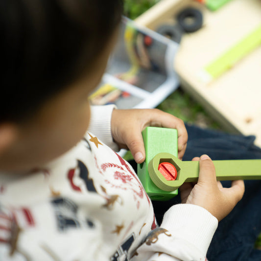 Child playing with a toy tool set outdoors