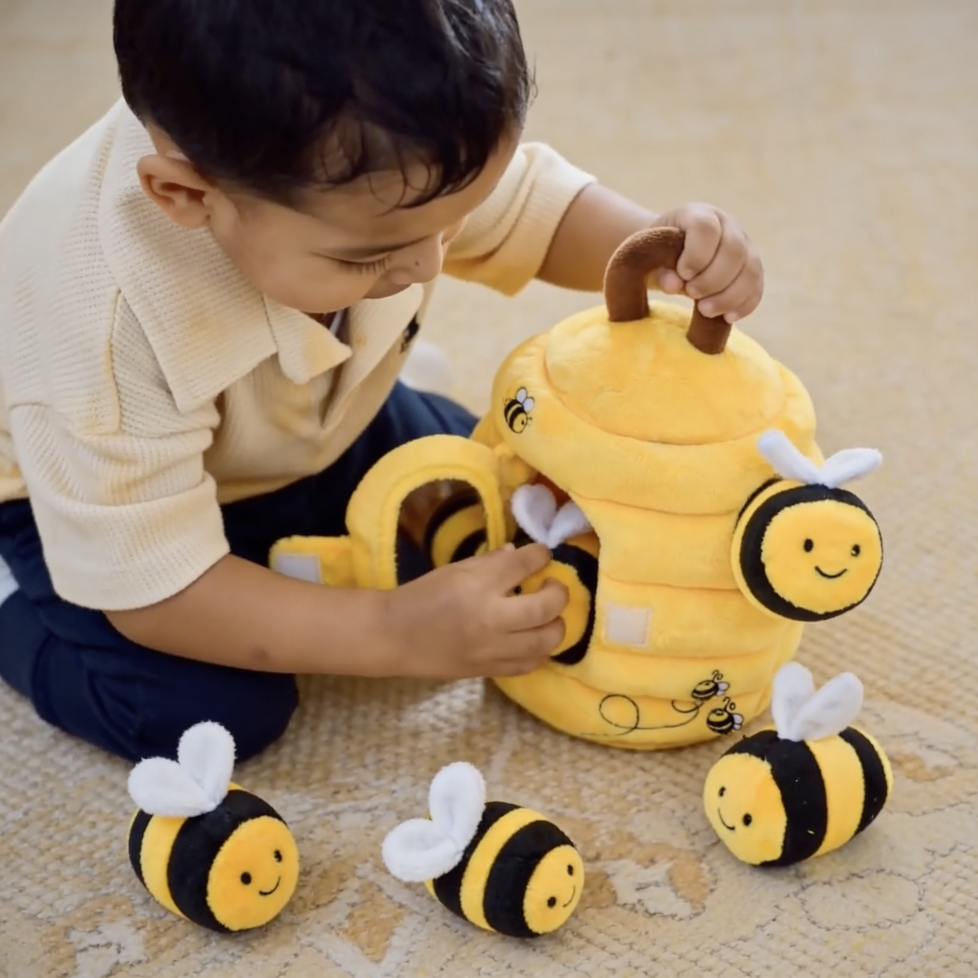 Child playing with a plush bee toy on a carpeted floor